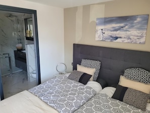 A bedroom with a bed, a bedside table, a mirror, and a painting on the wall. - GITE DU RUISSEAU73 - BOURG SAINT MAURICE (BOURG SAINT MAURICE)