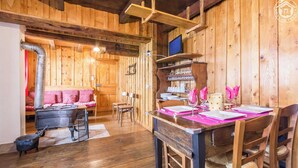 Une chaleureuse cabane en bois comprenant un coin repas, une cheminée et un lit avec une literie rouge.
