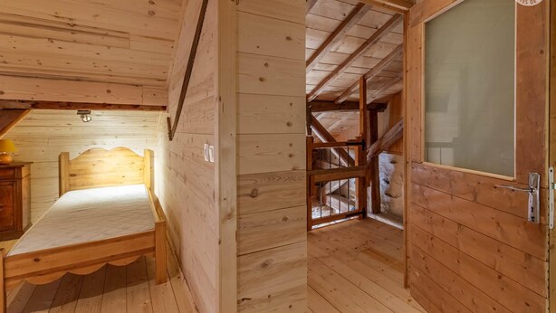 Une pièce en bois avec un lit, une porte et une fenêtre.