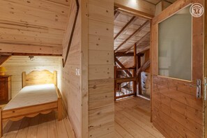 A wooden room with a bed, a door, and a window.