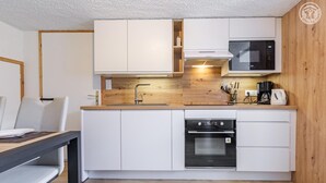 Eine moderne Küche mit weißen Schränken, einem Einbauofen, einer Mikrowelle und einer Kaffeemaschine.