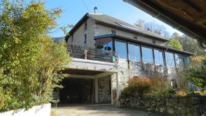 A two-story house with a balcony, a garage, and a stone wall. - L'ECLAIRCIE - THOIRY (THOIRY)