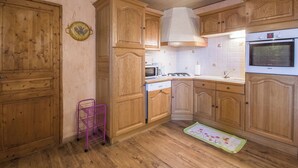 A kitchen with wooden cabinets, a Bosch oven, and a purple metal stool. - L'ECLAIRCIE - THOIRY (THOIRY)