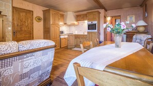 A cozy kitchen with wooden cabinets, a dining table set for four, and a flower vase on the table. - L'ECLAIRCIE - THOIRY (THOIRY)