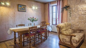 A dining area with a wooden table and chairs, a vase of flowers, and a patterned armchair. - L'ECLAIRCIE - THOIRY (THOIRY)