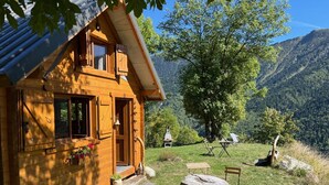 Une cabane en bois avec une véranda, une table en pierre et des sièges d’extérieur.