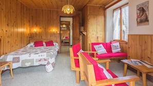 A wooden room with a bed, two red sofas, a wooden table, and a window. - LES GENTIANES - REGUET (NOTRE DAME DE BELLECOMBE)
