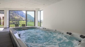 Ein modernes Indoor-Whirlpool mit Blick auf eine Berglandschaft durch große Fenster.