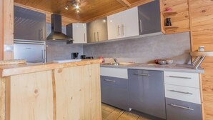 Une cuisine moderne avec des meubles en bois, un réfrigérateur en acier inoxydable et un plan de travail gris.