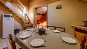 A dining area with a round table set for four, a microwave, and a small refrigerator.