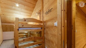 A wooden interior with bunk beds, a wooden ceiling, and a door with a logo.