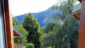 A balcony with a table and chairs, overlooking a mountainous landscape.