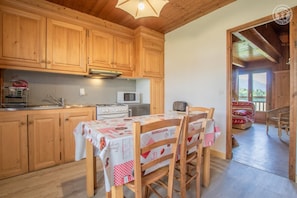 A kitchen with wooden cabinets, a stove, a microwave, and a table with chairs.