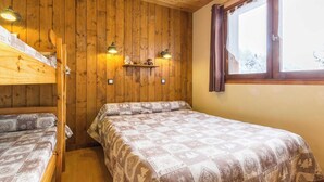 Una habitación con paneles de madera, literas, una ventana con cortinas e iluminación en la pared.