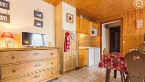 Una cocina acogedora con armarios de madera, un microondas y una zona de comedor con mesa y sillas.