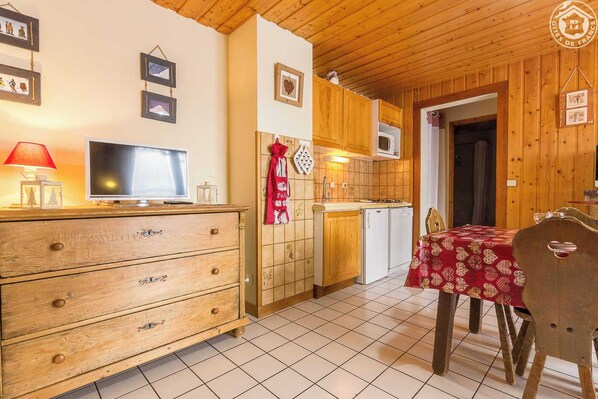 Una cocina acogedora con armarios de madera, un microondas y una zona de comedor con mesa y sillas.