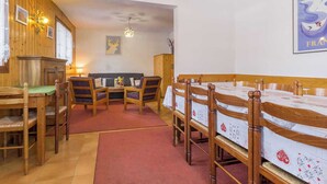 Een gezellige kamer met houten meubels, een bank en een tafel met stoelen.