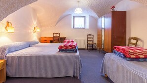 Een knus slaapkamer met twee bedden, een houten dressoir, een stoel en een raam.