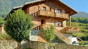 Eine Holzhütte mit Steinunterbau, Holzbalkonen und einer Treppe, die zum Obergeschoss führt.