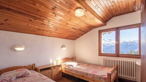A cozy bedroom with wooden ceilings and a large window offering a mountain view. - CHALET MATTIVI - HAUTELUCE LES SAISIES (HAUTELUCE LES SAISIES)