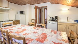 A cozy kitchen with a dining table, wooden chairs, a microwave, a refrigerator, a coffee maker, and a dishwasher. - CHALET MATTIVI - HAUTELUCE LES SAISIES (HAUTELUCE LES SAISIES)