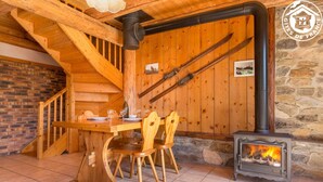 Un interior de madera con una mesa de comedor, sillas, chimenea y una escalera.