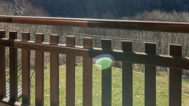 Un balcón de madera con vistas a montañas nevadas y un cielo despejado.