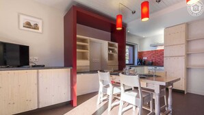 Una cocina moderna con armarios de madera, una mesa de comedor con sillas e iluminación colgante.