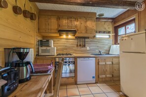 A compact kitchen with wooden cabinets, a microwave, a coffee maker, a dishwasher, and a refrigerator.