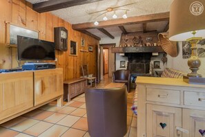 Ein rustikaler Innenraum mit Holzwänden, einem Kamin, einem Fernseher und einem Essbereich.