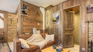 A cozy living room with a brown sofa, a wooden coffee table, and a stone wall. - LE BIVOUAC - AUSSOIS (AUSSOIS)