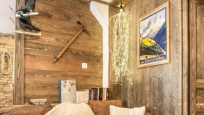 A cozy living room with a wooden wall, a brown sofa, a coffee table with bowls and a teapot, and a poster on the wall. - LE BIVOUAC - AUSSOIS (AUSSOIS)