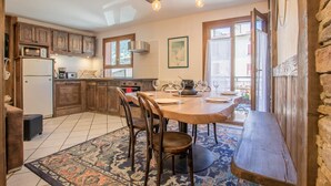 A cozy kitchen with wooden cabinets, a dining table with chairs, and a bench. - LE BIVOUAC - AUSSOIS (AUSSOIS)