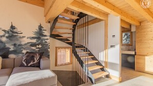Un interior moderno con una escalera de caracol, un sofá y un cuadro con árboles.