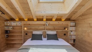 Una habitación acogedora de madera con tragaluces, una cama con almohadas y estanterías.