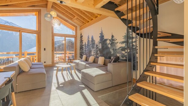 Un salón amplio con un ventanal grande, una escalera y una zona de estar acogedora.