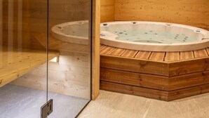 Un spa con sala de madera, dos tinas de hidromasaje y una mampara de vidrio.