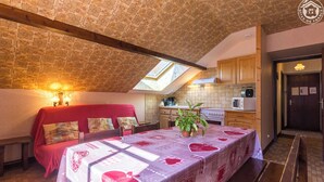 Une chambre confortable avec un lit, une table agrémentée d’une plante, et un coin cuisine doté de meubles en bois et d’un four à micro-ondes.
