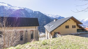 Un village de montagne aux bâtiments traditionnels, avec une piste de ski et des montagnes enneigées en toile de fond.