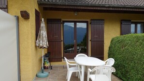 A patio with a white table and chairs, a small table with a bag, and a potted plant. - LA PLANTAZ - CLERY - Gîte (CLERY)