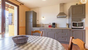 A compact kitchen with grey cabinets, a microwave, a coffee maker, and a dining table with chairs. - LA PLANTAZ - CLERY - Gîte (CLERY)