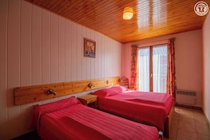 A room with two beds, wooden headboards, a small table, a nightstand, a painting on the wall, and a window with curtains. - Self-catering - ALBIEZ MONTROND (ALBIEZ MONTROND)