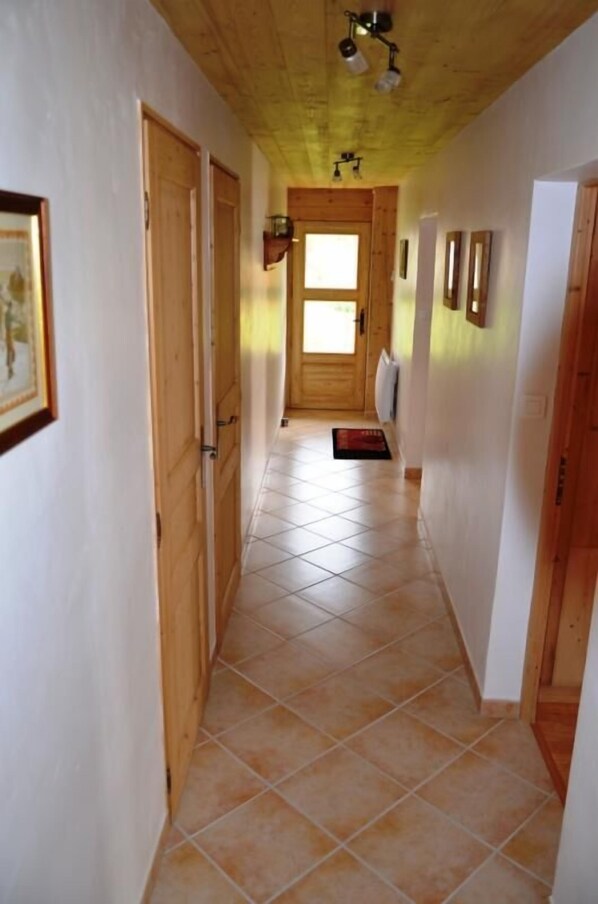 A hallway with wooden doors, a tiled floor, and a wooden ceiling. - LE CREY - CREST VOLAND COHENNOZ (CREST VOLAND COHENNOZ)