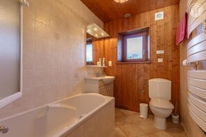 A bathroom with a bathtub, sink, and toilet. - LE CREY - CREST VOLAND COHENNOZ (CREST VOLAND COHENNOZ)