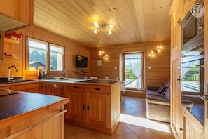 A wooden cabin with a kitchen, dining area, and a sofa.