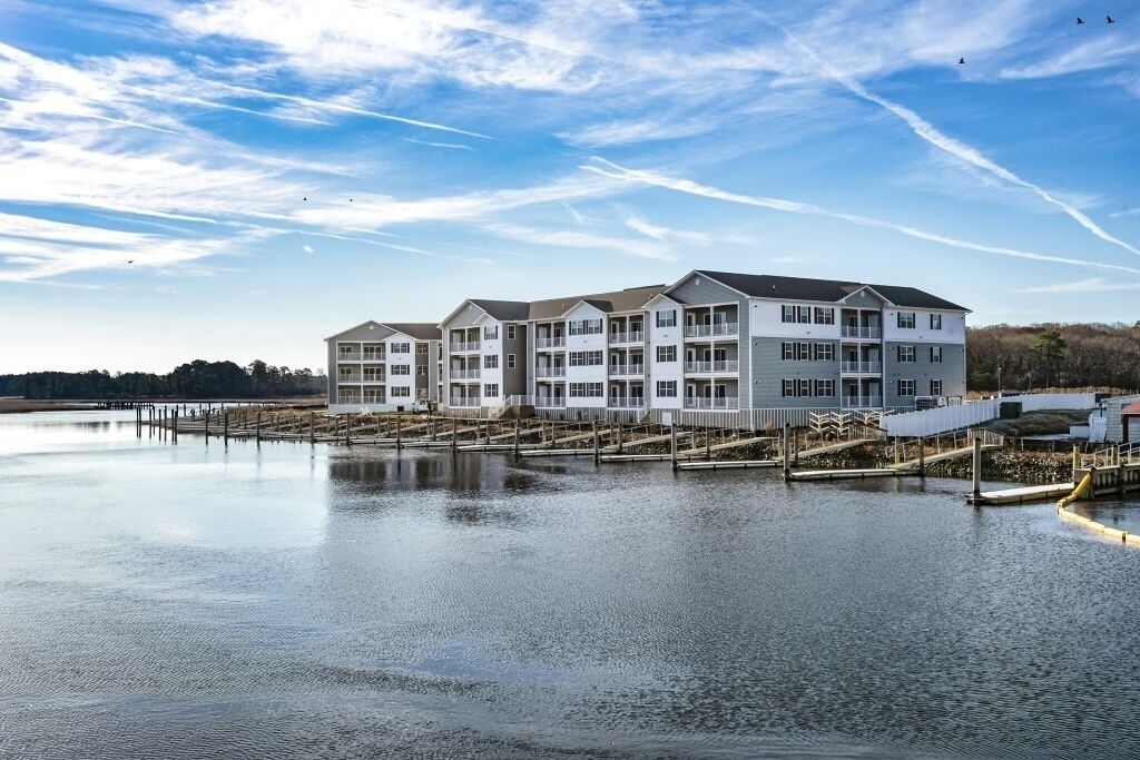 A multi-story hotel with a waterfront view, featuring balconies and a dock.