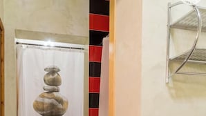 A hallway with a tiled floor, a curtain with a stone stack reflection, and a metal shelf on the wall.