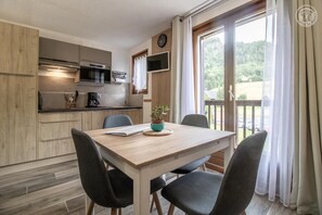 A modern kitchen with wooden cabinets, a built-in oven, and a dining area with a table and chairs.