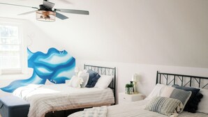Ein Schlafzimmer mit zwei Betten, einem Deckenventilator und einer großen Wandmalerei.