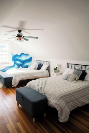 Une chambre avec deux lits, un ventilateur de plafond et une grande fresque murale.